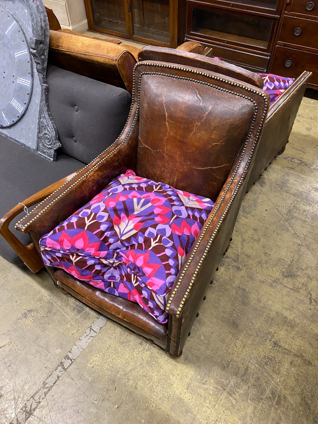A pair of early 20th century studded tan leather armchairs, width 66cm, depth 76cm, height 88cm